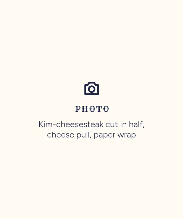 Photo placeholder: Kim-cheesesteak cut in half, cheese pull, paper wrap